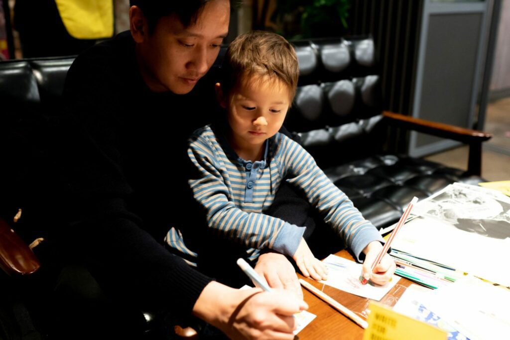 A young father and his son writing letters for Write For Rights.